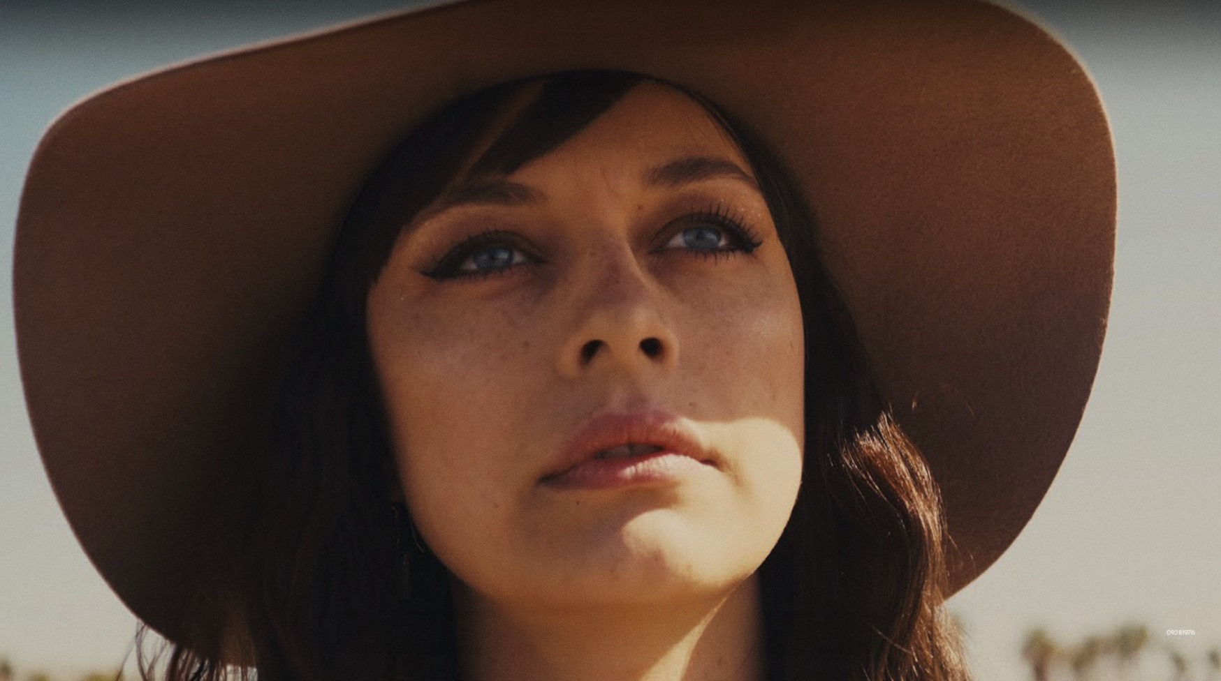 Close-up of a woman wearing a wide-brimmed hat in warm outdoor light