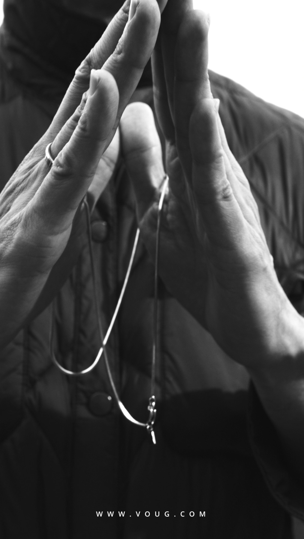 Black-and-white photograph of hands holding a necklace