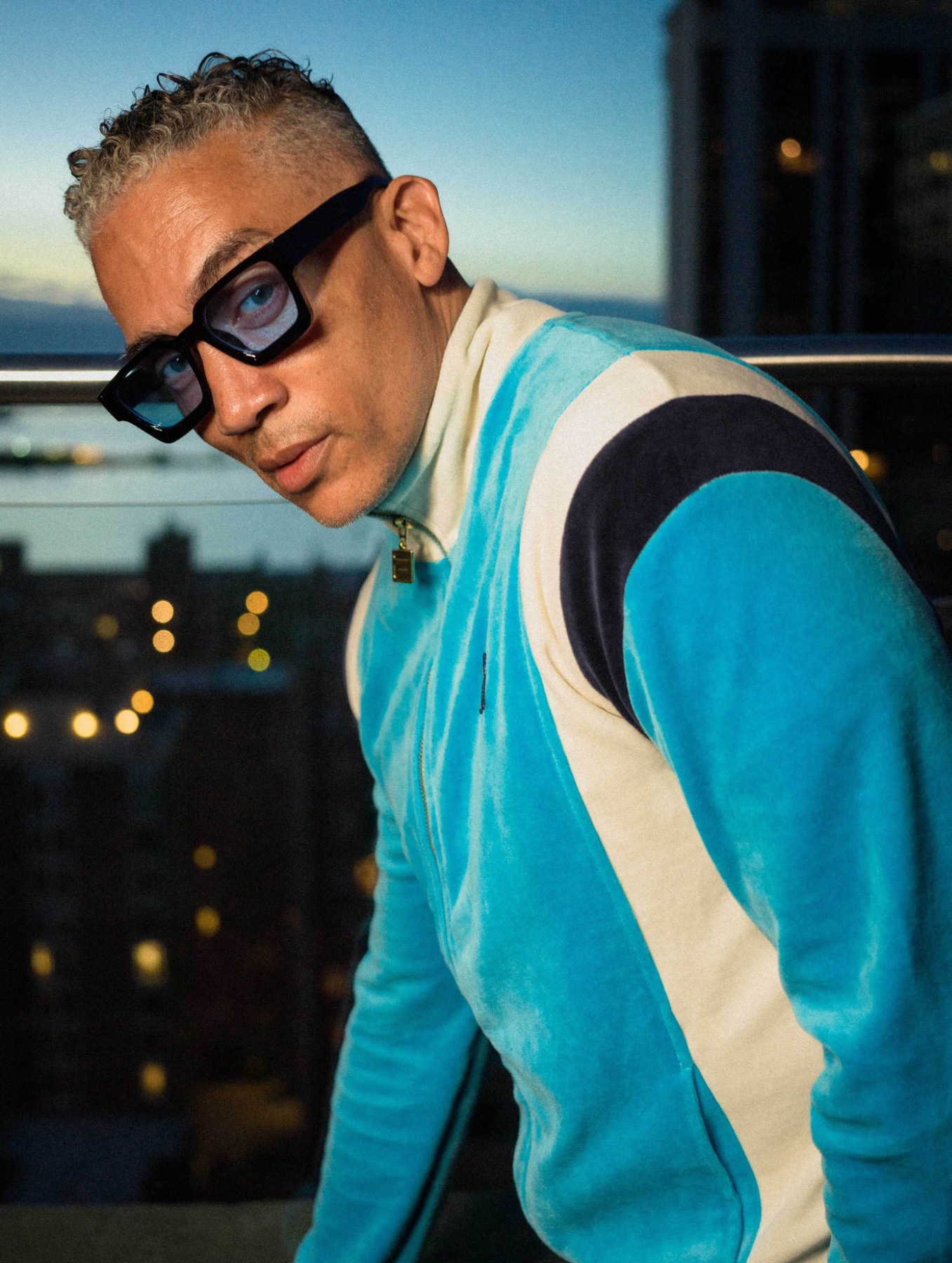 A model in sunglasses and a blue jacket outside at night