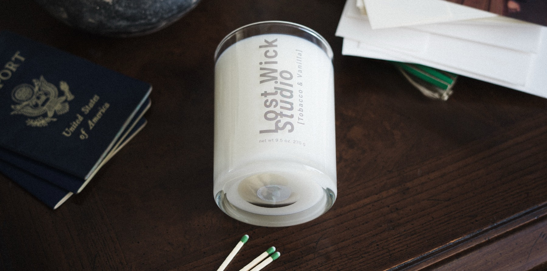 Lost Wick Studio candle styled with books and objects on a dark tabletop
