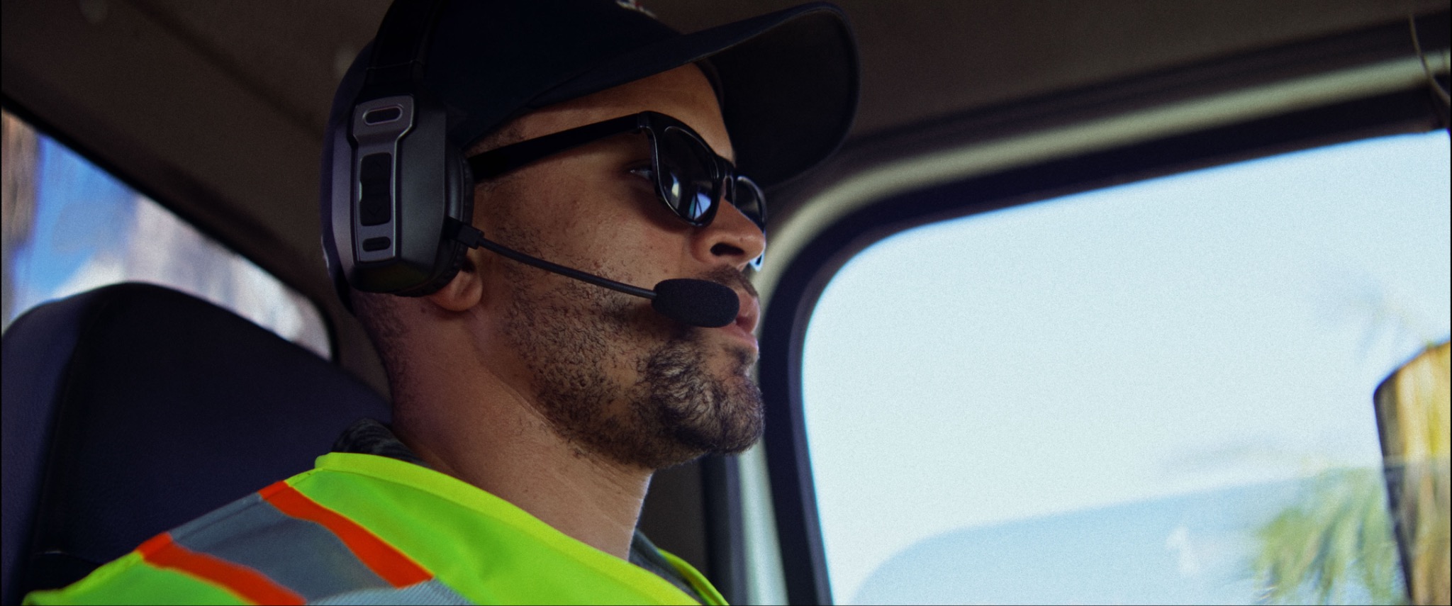 Driver wearing a Black & Gray headset inside a work vehicle
