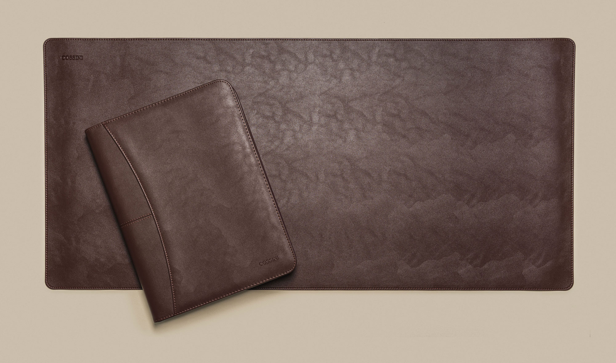 Brown Cossini padfolio arranged over a matching leather desk mat