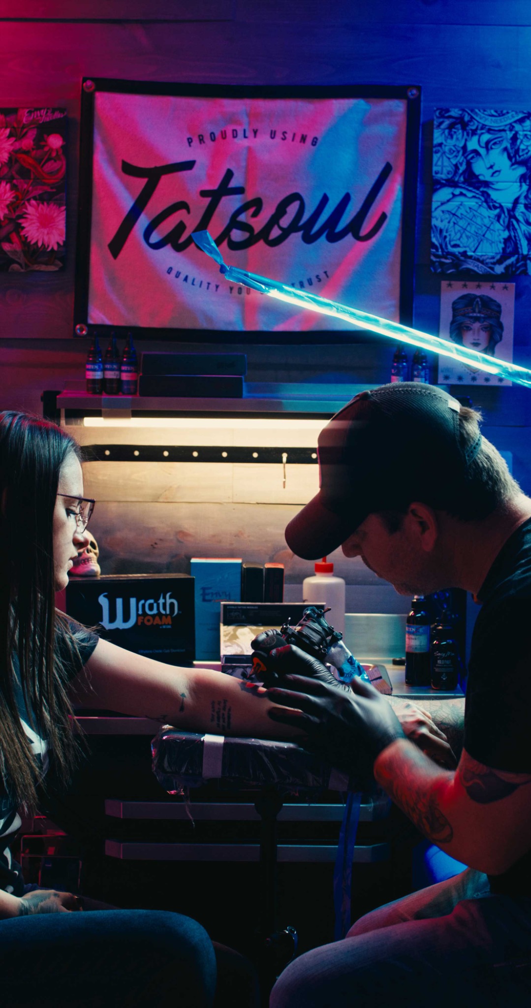 Tattoo artist working with TATSoul equipment in a color-lit studio